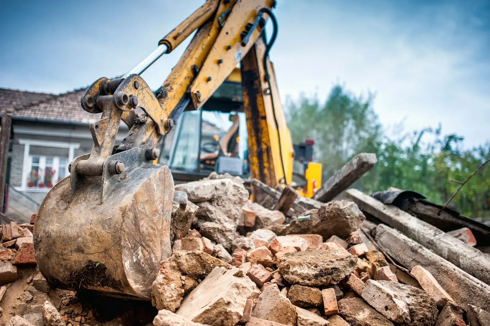 Excavator bucket breaking up concrete and brick rubble