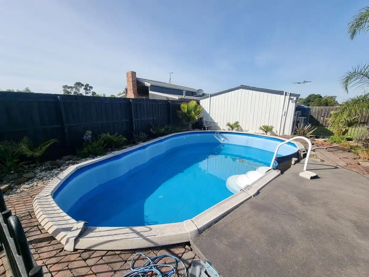 Fibreglass pool in a paved backyard before removal