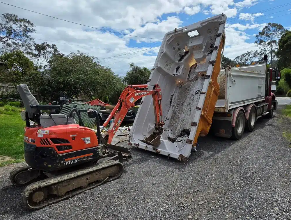 Removed fibreglass pool shell being loaded onto a tipper truck