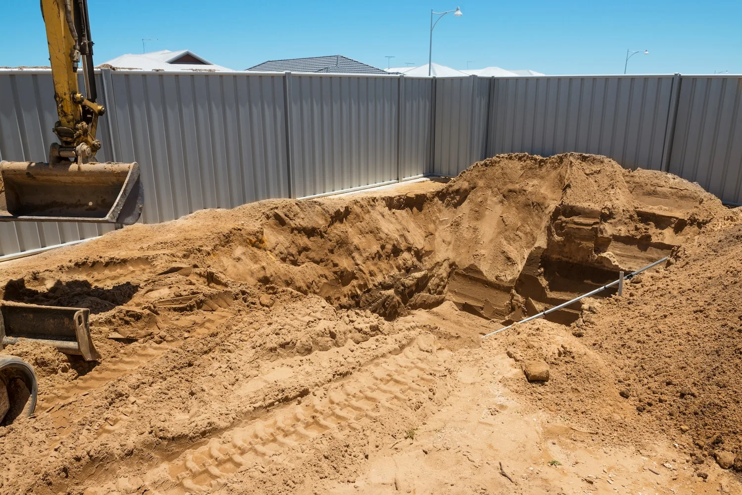 Excavator grading fill soil into a former pool area