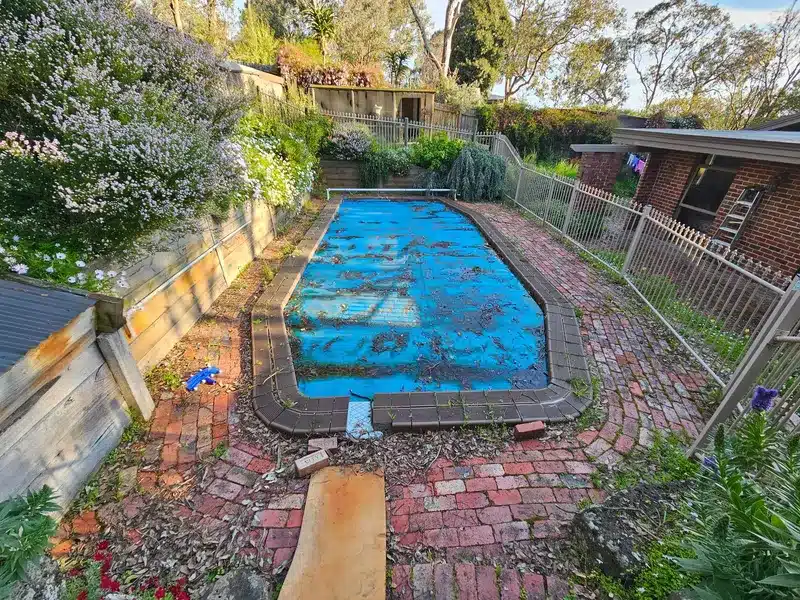 Before: covered pool with a brick surround beside a garden bed